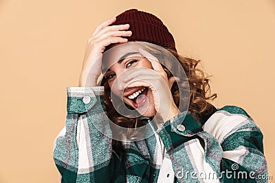 Photo of pretty joyful woman in knit hat laughing and covering her face Stock Photo