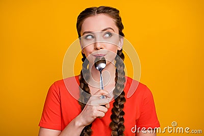 Photo of pretty teenager lady hold metal spoon in mouth desire dinner look dreamy empty space think of tasty food wear Stock Photo