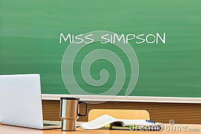 Photo of professor desk in classroom with Miss Simpson name written in black board Stock Photo