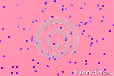 Photo of purple hearts glitter sprinkles on pink trendy background. Festive holiday background for your projects. Celebration Stock Photo