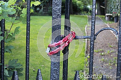 Red lock tied around black entrance gate Stock Photo