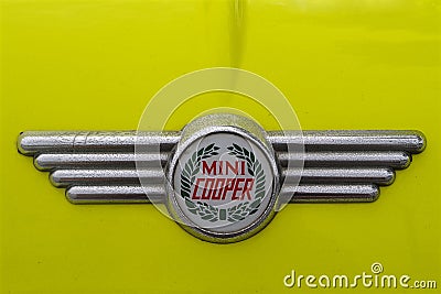 Photo of a retro Mini Cooper car logo badge on a yellow Mini Cooper car. Editorial Stock Photo