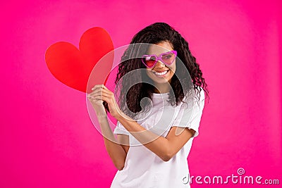 Photo of romantic curly millennial lady hold heart look empty space wear white t-shirt isolated on pink color background Stock Photo