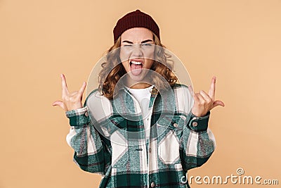 Photo of sassy young woman winking and making horns with fingers Stock Photo