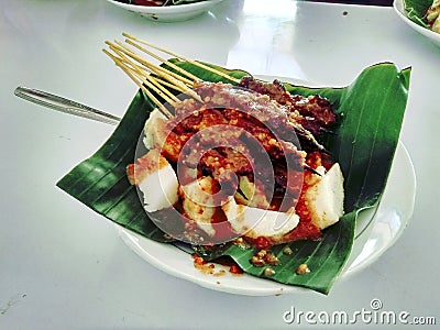 Photo of Sate Beef Suruh, typical of Salatiga Indonesia. Served with Lontong, on a plate covered with leaves. Editorial Stock Photo