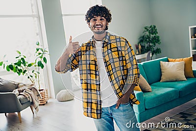 Photo of satisfied glad person demonstrate thumb up confirmation bright interior living room house indoors Stock Photo