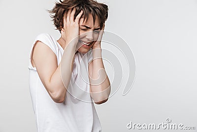 Photo of scared woman with short brown hair in basic t-shirt grabbing her head and crying Stock Photo