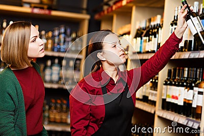 Photo of seller and buyer on blurred background of racks with bottles of wine Stock Photo