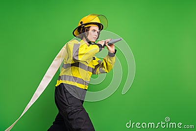 Photo of serious reliable firewoman dressed yellow uniform helmet holding fire hose looking empty space isolated green Stock Photo