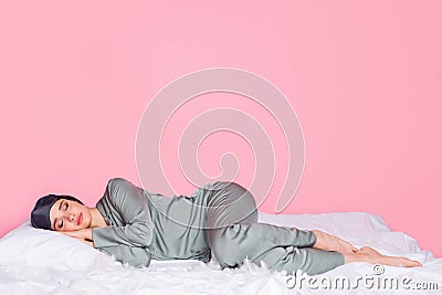 Photo of shiny adorable young lady sleepwear smiling lying blanket closed eyes isolated pastel pink color background Stock Photo