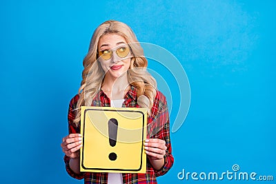 Photo of shiny sweet young lady wear plaid shirt holding exclamation point board looking empty space isolated blue color Stock Photo