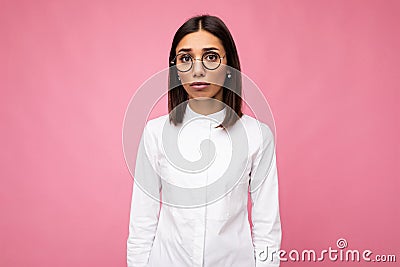 Photo shot of beautiful sorrowful young brunette woman wearing casual clothes and stylish optical glasses isolated over Stock Photo