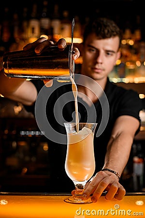 photo shot of the process of pouring cocktail from shaker with strainer into glass Stock Photo