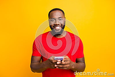 Photo of simple good cute handsome black man holding his phone with both hands smiling at camera while isolated with Stock Photo