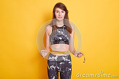 Photo of slim lady wearing sports clothing, holding measure tape, measuring her wrist, comparing her results after fitness Stock Photo