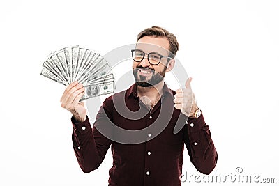 Smiling young man holding money showing thumbs up. Stock Photo