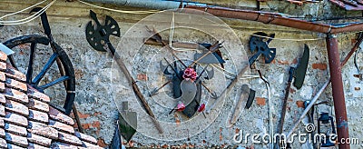 Photo of some medieval weapons and objects placed on a wall at the entrance of a small museum in the Rasnov Citadel - Rasnov, Stock Photo