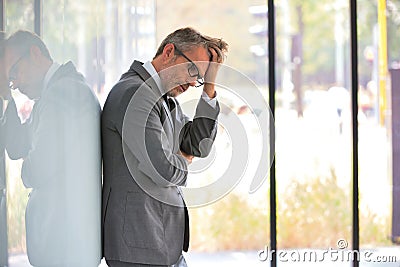 Stressed mature businessman standing at office Stock Photo