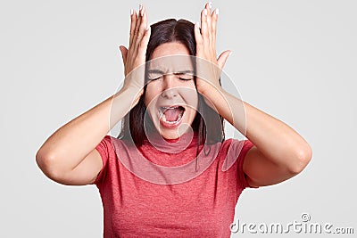 Photo of stressful brunette female has terrible headache, being in panic as lost her close person, feels desperate, isolated over Stock Photo