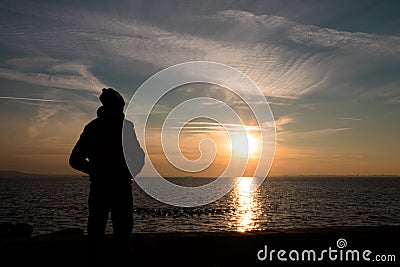 Photo of the sunset with the silhouette of a young man. Stock Photo