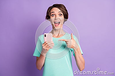 Photo of surprised adorable young lady wear casual teal outfit pointing phone purple color background Stock Photo