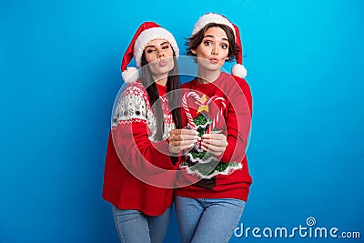 Photo of sweet flirty women santa elf wear ornament pullovers holding x-mas candies sending kiss isolated blue color Stock Photo
