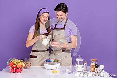 Photo of sweet positive boyfriend girlfriend dressed preparing domestic kefir isolated purple color background Stock Photo