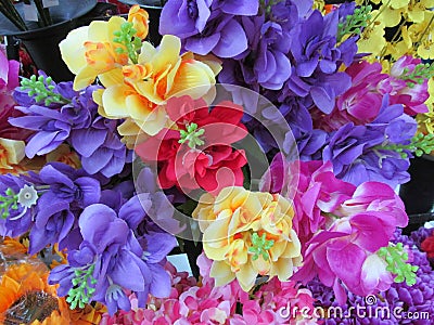 A cluster of very colorful artificial fake flowers on display Stock Photo