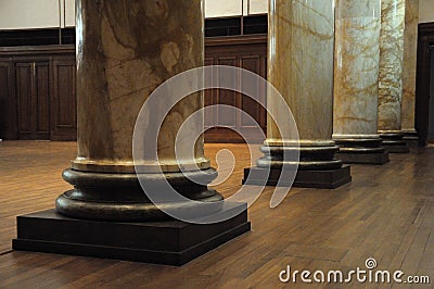 A few marble stone graphite granite supporting pillars in a hall with wooden timber floor Stock Photo