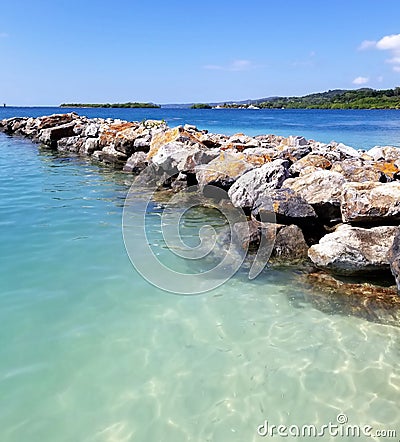 Crystal clear ocean water next to natural rock breakwater off the shore of Roatan Honduras Stock Photo