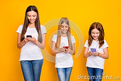 Photo of three funny ladies holding telephones in hands wear casual clothes isolated yellow background Stock Photo