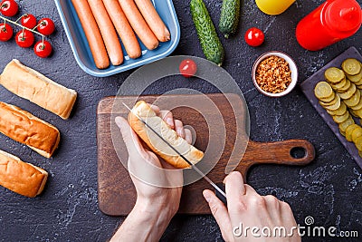 Photo on top of table with ingredients for hot dogs, cutting board, man`s hands Stock Photo