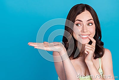 Photo of tricky cunning girl dressed green dress finger lips holding arm empty space isolated blue color background Stock Photo