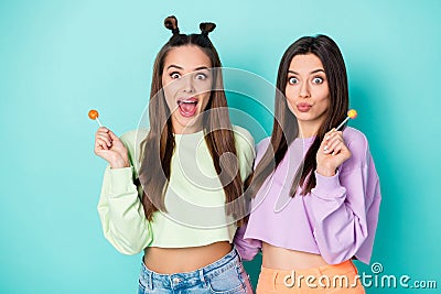 Photo of two funny cheerful ladies hold lollipop chupa chups hands crazy childish mood wear cropped pullovers naked Stock Photo