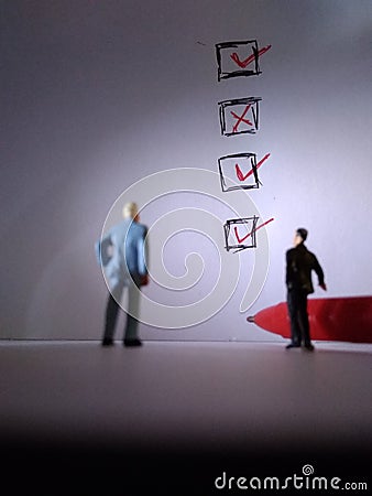 Two standing businessman mini figure toys, meeting, check list Stock Photo