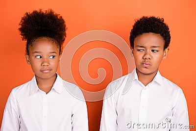 Photo of two young preteen black kids unhappy upset suspicious think isolated over orange color background Stock Photo