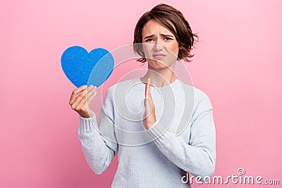 Photo of unhappy upset sad young woman hold blue heart paper shape hand refuse isolated on pink color background Stock Photo