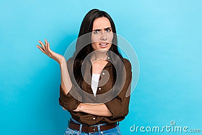 Photo of unsatisfied young woman wear brown shirt confused wtf misunderstanding irritated pretense isolated on blue Stock Photo