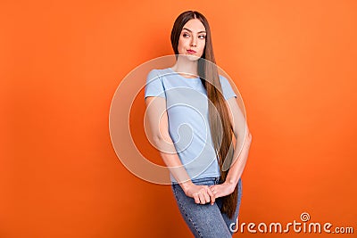 Photo of unsure brown hairdo young lady hold hands look empty space wear blue t-shirt isolated on vivid orange color Stock Photo