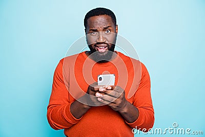 Photo of unsure man mixed-race looking at you with arrogance holding telephone browsing through this to find truthful Stock Photo
