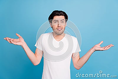 Photo of unsure troubled guy shrug shoulders confused face wear white t-shirt isolated blue color background Stock Photo