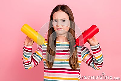 Photo of upset dissatisfied little funny girl kid grimacing pouring out sauces dislike spicy mustard on pink Stock Photo