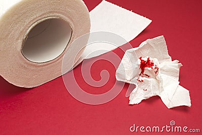 A photo of used bloody toilet paper and a tiolet paper roll. Blood drops and traces. Hemorrhoids, constipation treatment health pr Stock Photo