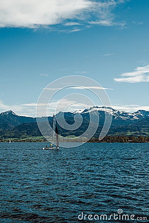 Sailboats on Lake Chiem and snow-capped mountains in the distance Stock Photo