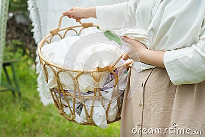 A photo of a woman holding a basket of freshly laundered clothes against the backdrop of an outdoor laundry line Stock Photo