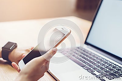 Photo of a woman holding a blank screen phone and a computer. and put a smart watch, film effect. Stock Photo