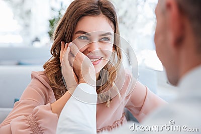 Photo of woman in love looking on her man and taking pleasure when holding male hand at her face, while having date in restaurant Stock Photo