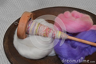 Wood spindle with hand spun yarn in a wood bowl of wool roving Stock Photo