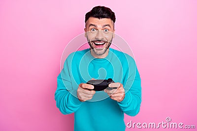 Photo of young addicted console gamer man student wear blue sweatshirt hold gamepad interested action isolated on pink Stock Photo