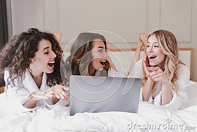 Photo of young excited women 20s wearing white housecoat lying i Stock Photo